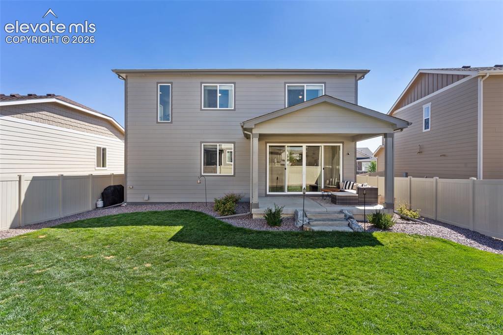 Image 31 of 33: Spacious backyard with a covered patio, multiple windows on the rear facade