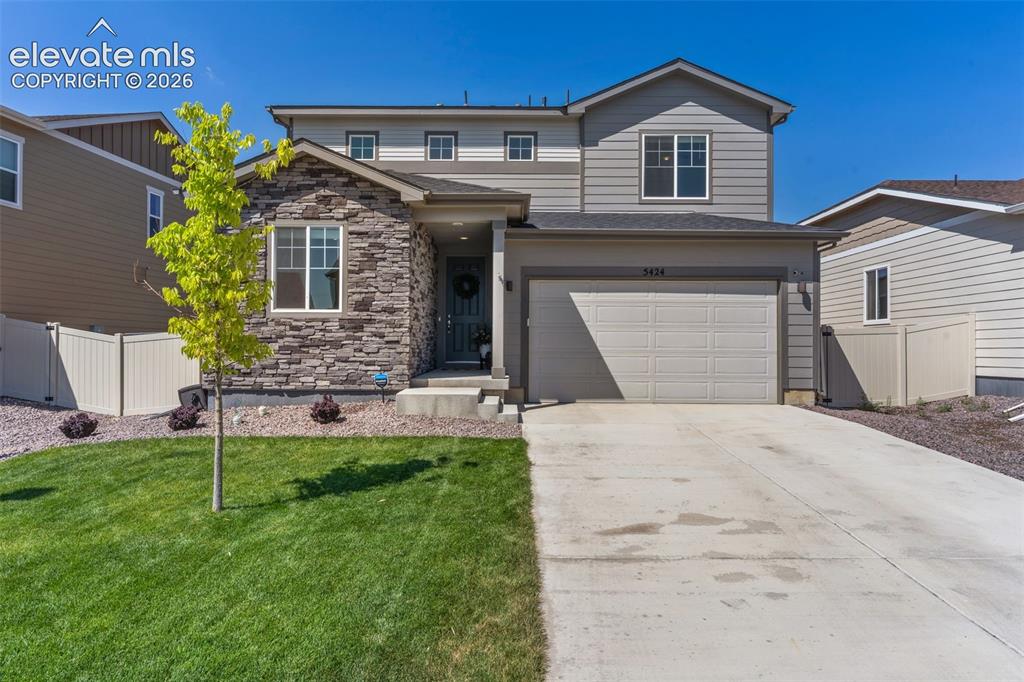 Image 5 of 33: Two-story residence featuring a stone and siding facade, an attached two-ca