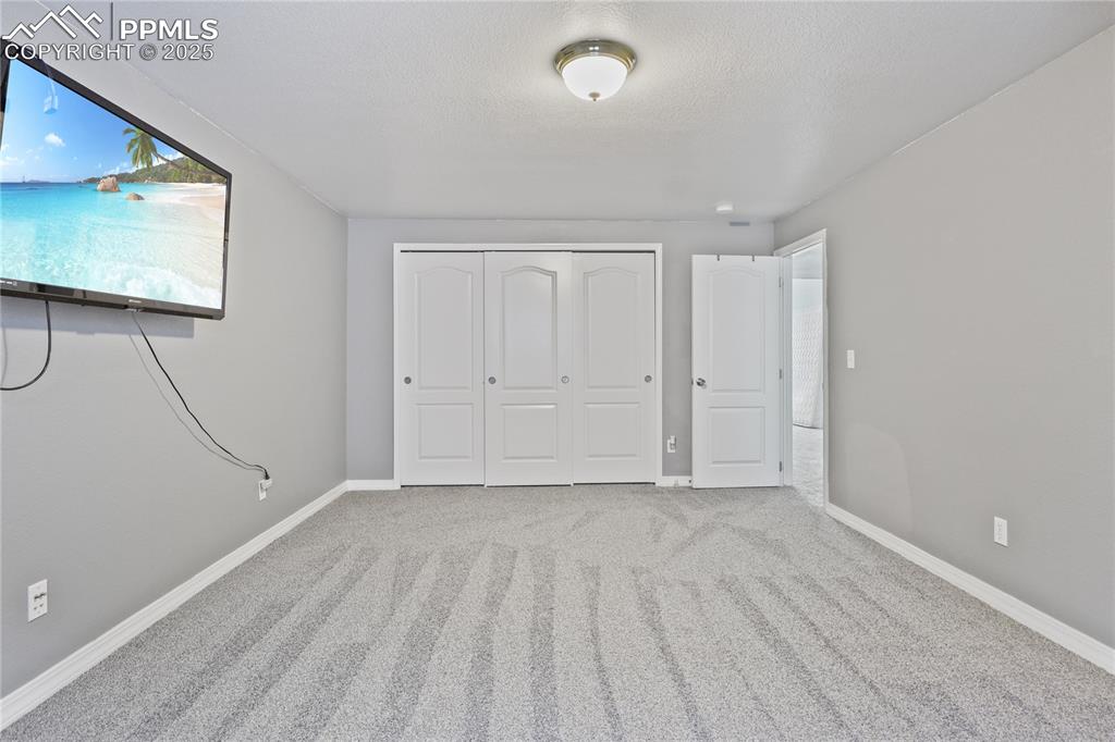 Image 30 of 45: Unfurnished bedroom featuring baseboards, a closet, carpet floors, and a te