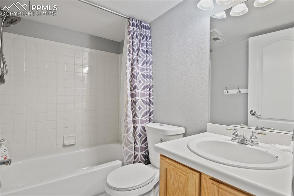 Image 31 of 45: Full bathroom featuring visible vents, toilet, vanity, shower / tub combo, 