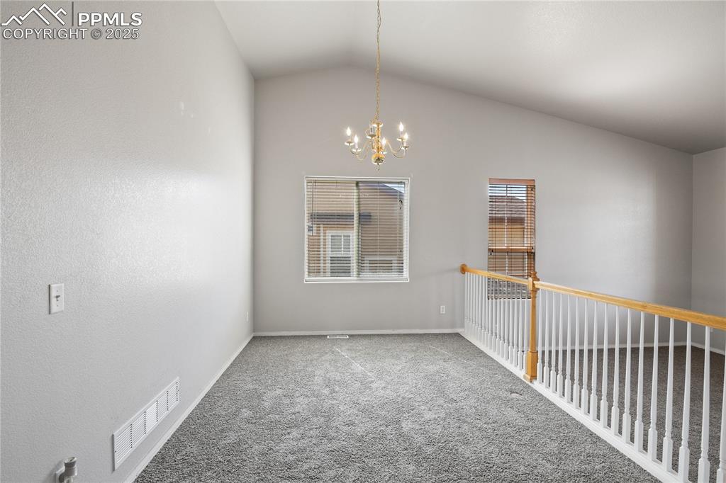 Image 6 of 25: Carpeted spare room featuring baseboards, lofted ceiling, visible vents, an