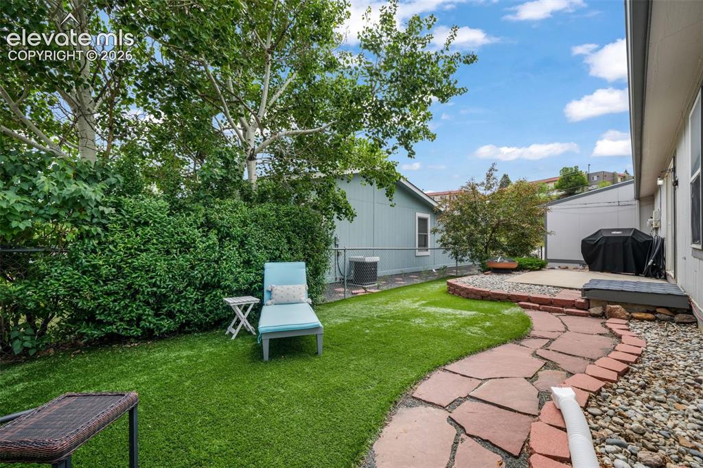 Image 4 of 50: Ranch style home featuring a 2 car garage, mature landscaping, and paid off
