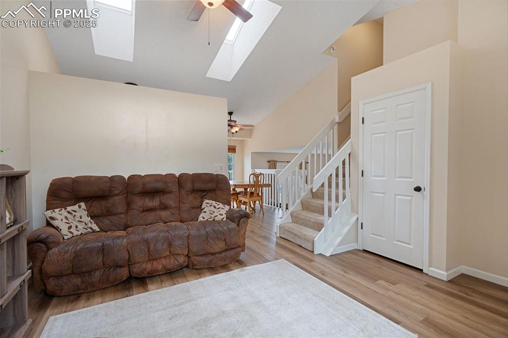 Image 11 of 33: Living room with ceiling fan, a skylight, high vaulted ceiling, wood finish