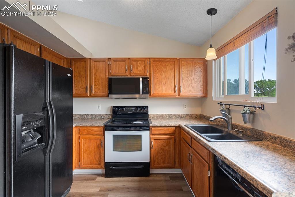 Image 13 of 33: Kitchen with black appliances, lofted ceiling, light wood-style floors, dec