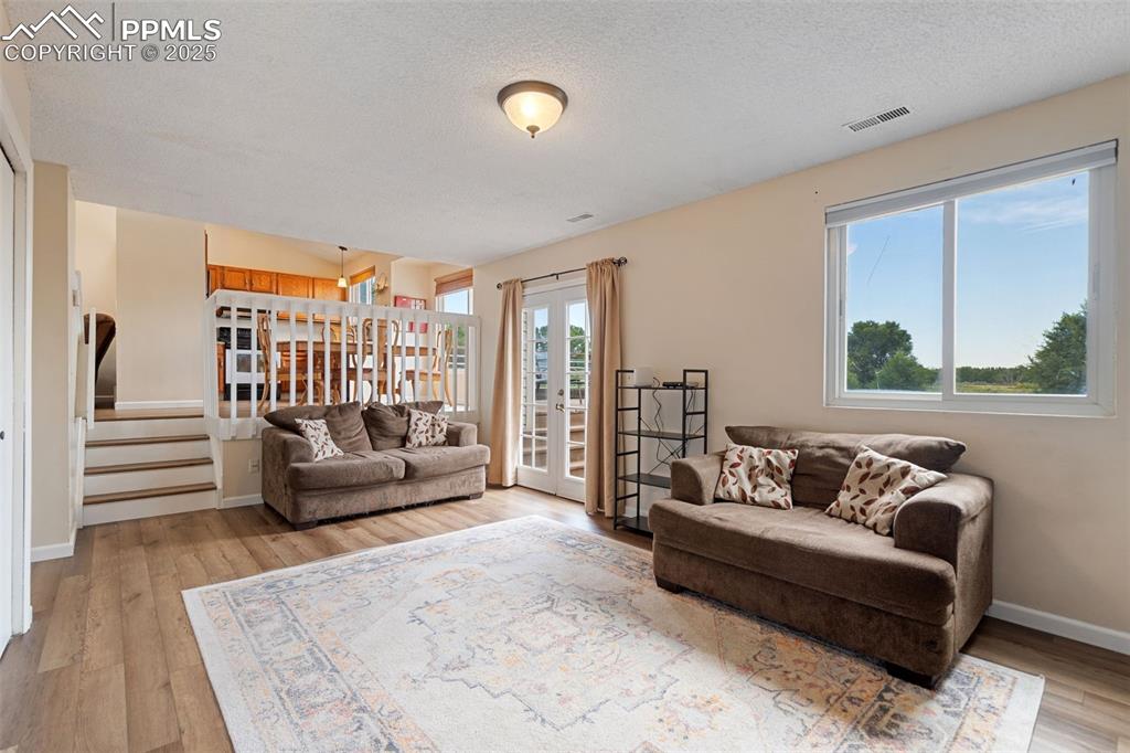 Image 18 of 33: Living area with light wood-style flooring, a textured ceiling, and stairs
