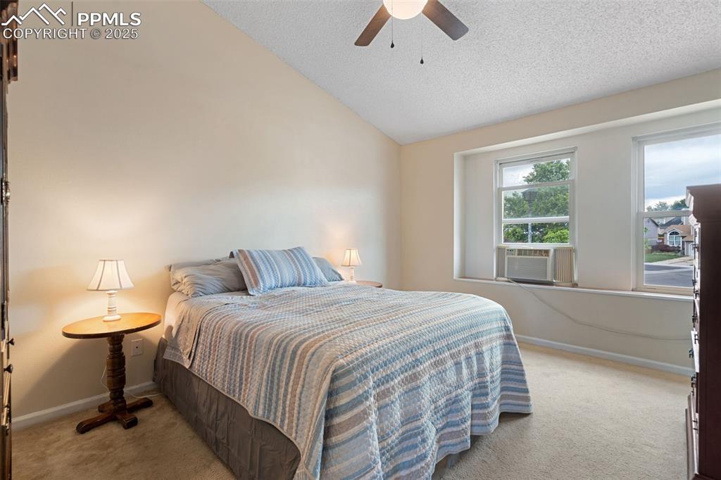 Image 19 of 33: Bedroom with carpet, vaulted ceiling, a textured ceiling, and a ceiling fan