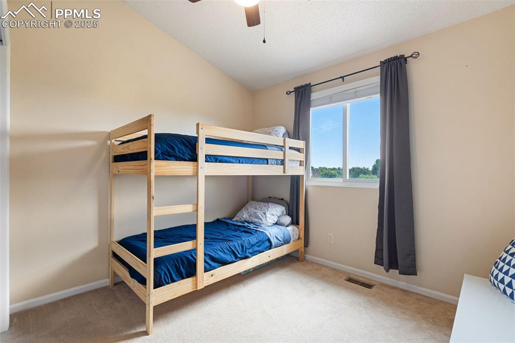 Image 22 of 33: Bedroom featuring carpet floors, lofted ceiling, a ceiling fan, and a textu