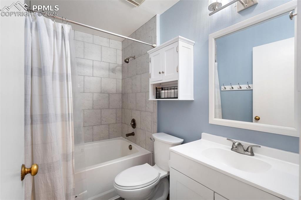Image 24 of 33: Bathroom featuring shower / tub combo with curtain and vanity
