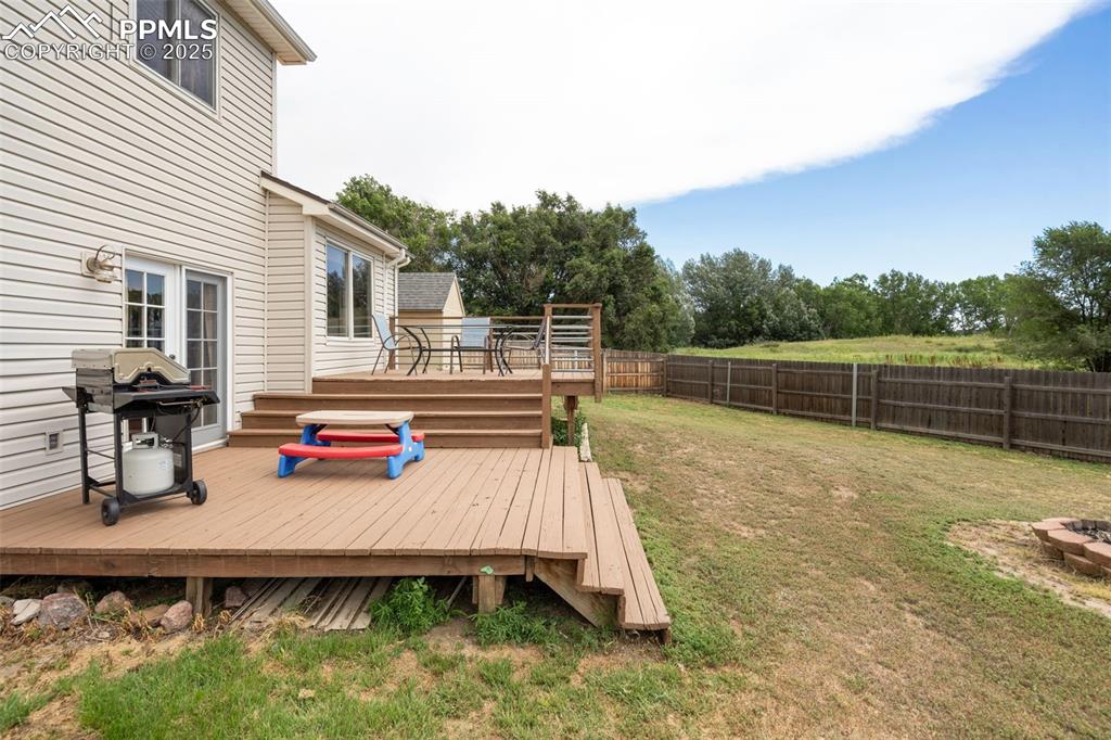 Image 25 of 33: Deck with grilling area and a fenced backyard