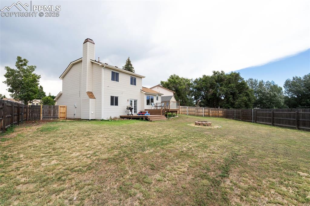 Image 29 of 33: Rear view of house with an outdoor fire pit, a fenced backyard, a wooden de