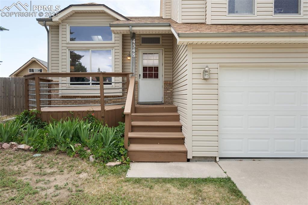 Image 5 of 33: Entrance to property featuring a garage, concrete driveway, and roof with s