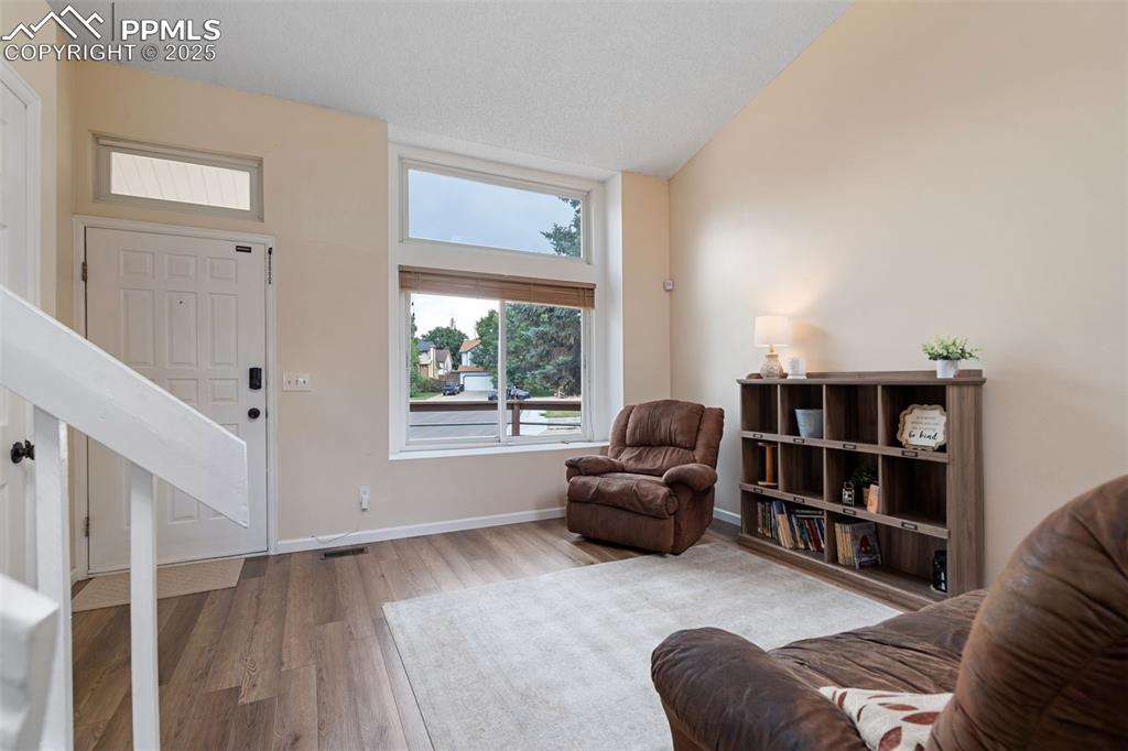 Image 9 of 33: Living area with vaulted ceiling and wood finished floors