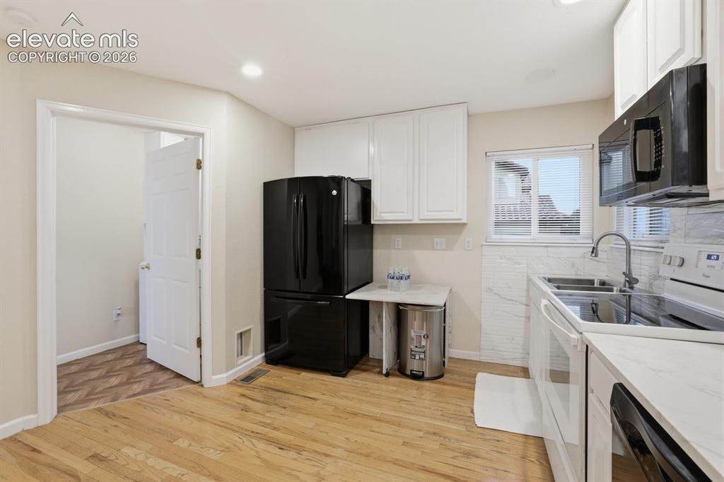 Image 11 of 45: Beautifully updated culinary space with white cabinetry, light wood-finish