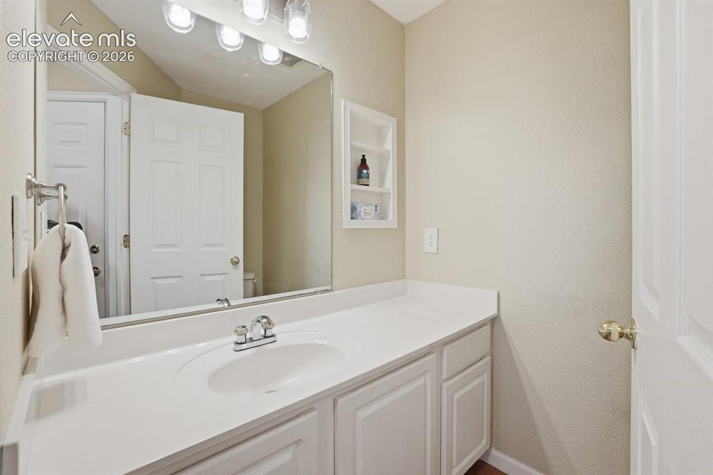 Image 13 of 45: Bathroom vanity featuring a white countertop with an integrated sink and ch
