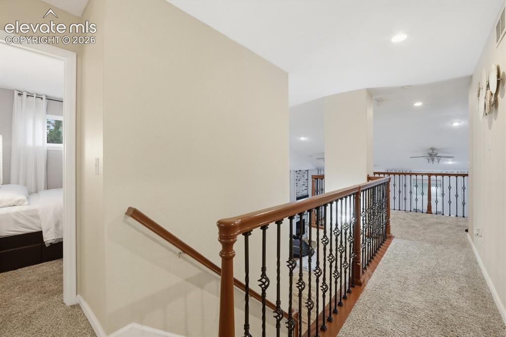 Image 14 of 45: Open upper-level hallway overlooking the dining and living areas, featuring