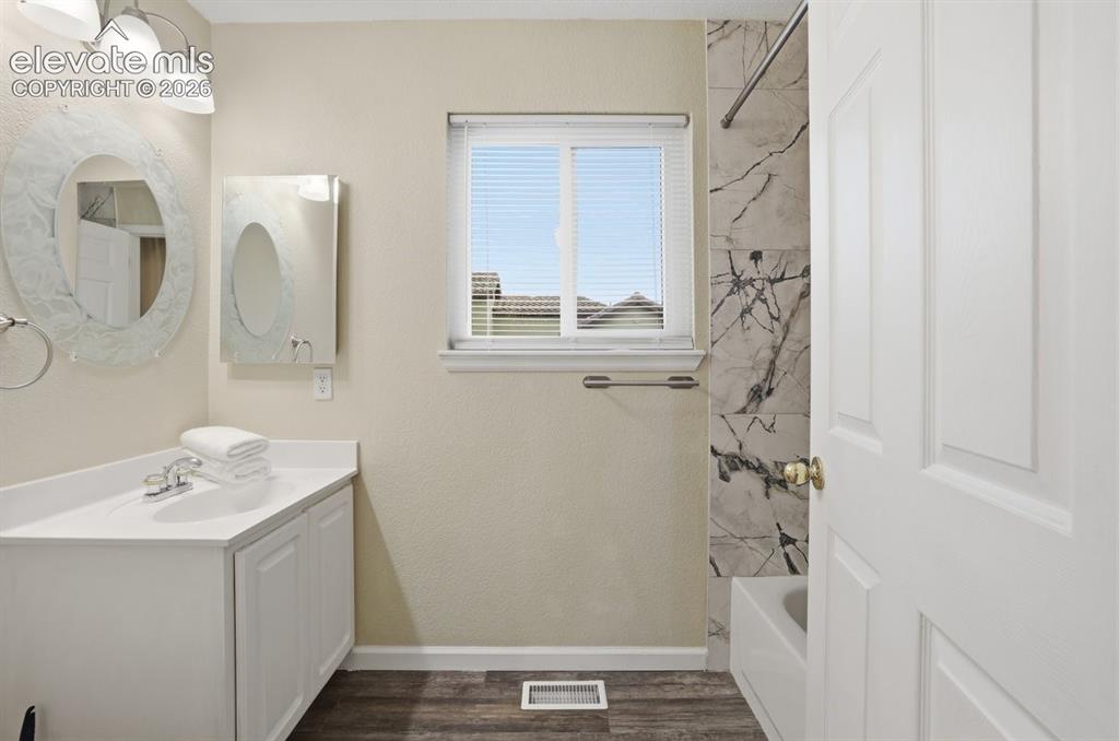 Image 17 of 45: Bathroom featuring a white vanity with integrated sink, chrome faucet, and 