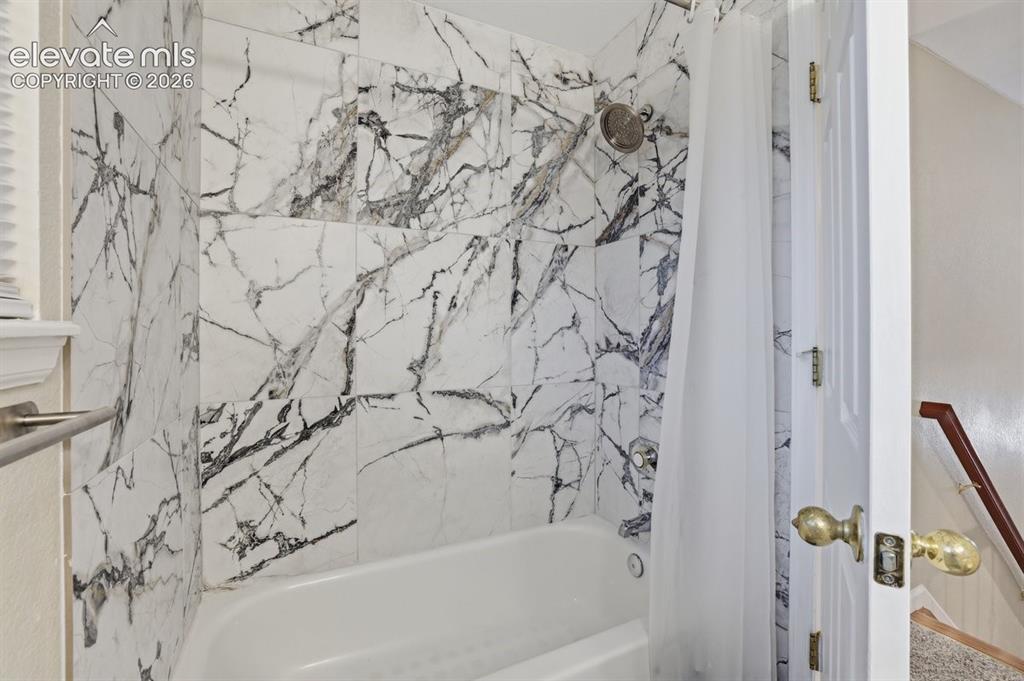 Image 18 of 45: Bathtub and shower combination featuring a rain shower head and white and g