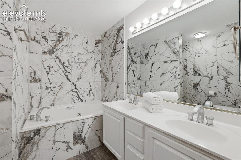 Image 22 of 45: Primary ensuite highlighting a corner jetted tub, dual-sink vanity with whi