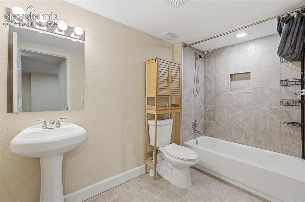 Image 33 of 45: Full lower-level bathroom featuring a tub/shower combination, pedestal sink