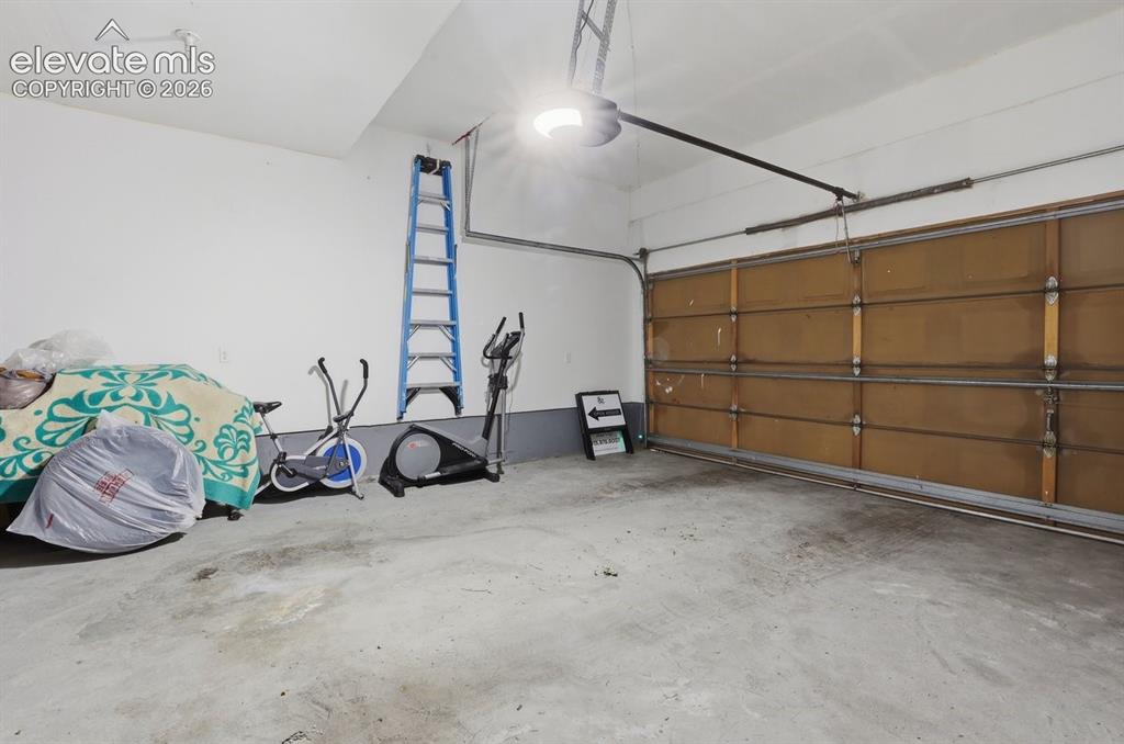 Image 38 of 45: Attached garage featuring concrete flooring, overhead lighting, and an auto