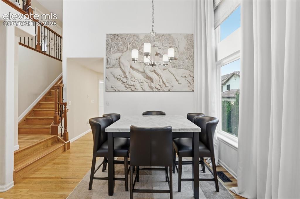 Image 6 of 45: Elegant dining area with soaring ceilings, hardwood flooring, and a large p