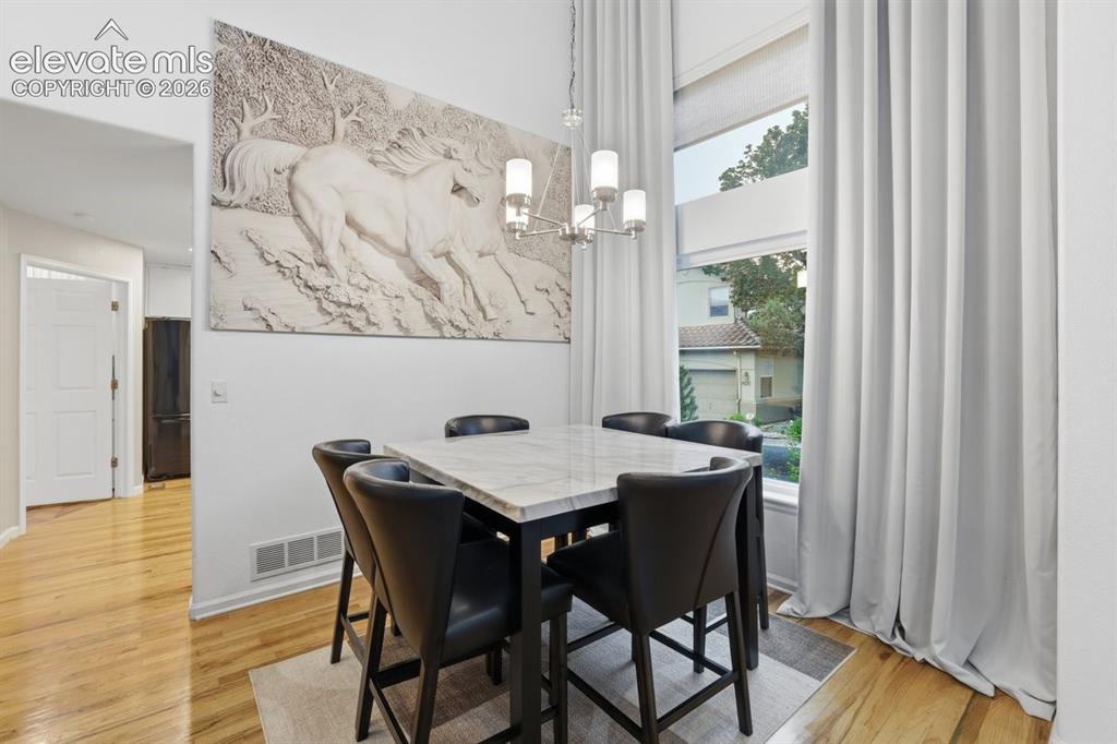 Image 7 of 45: Inviting dining area with a soaring ceiling, beautiful wood-finish flooring