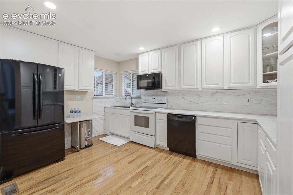 Image 9 of 45: Well-appointed kitchen featuring white shaker cabinetry, light-toned wood f