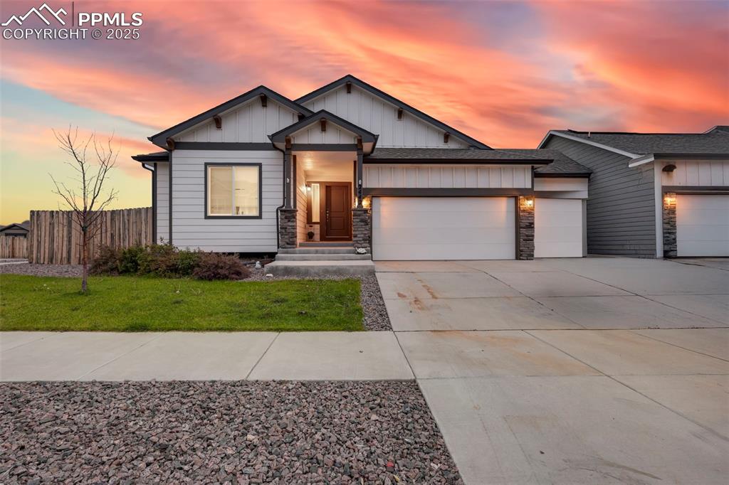 Caption: View of front of home featuring a garage, concrete driveway, board and batten siding, stone siding, 