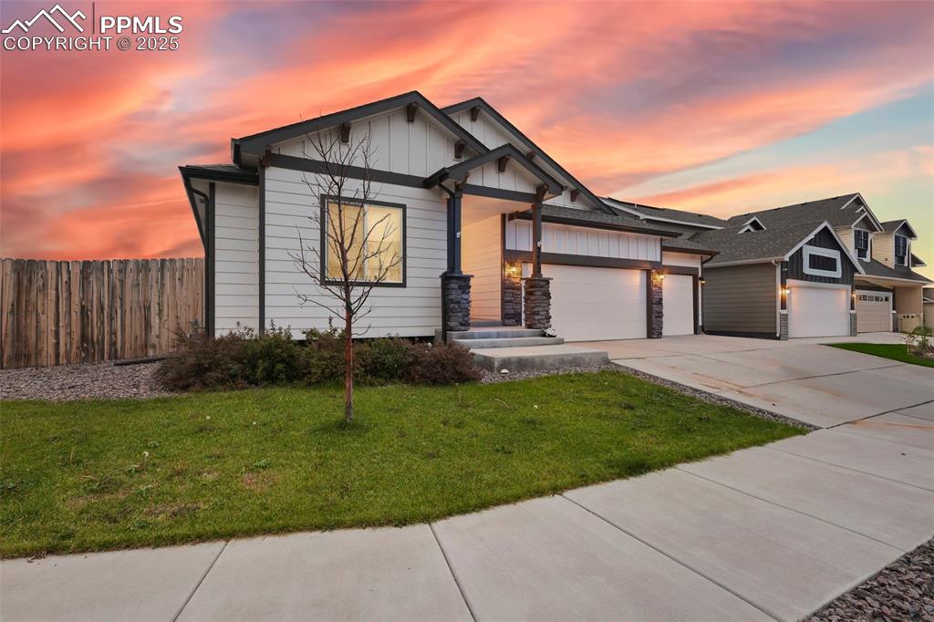Image 2 of 45: View of front of house with board and batten siding, driveway, a garage, an