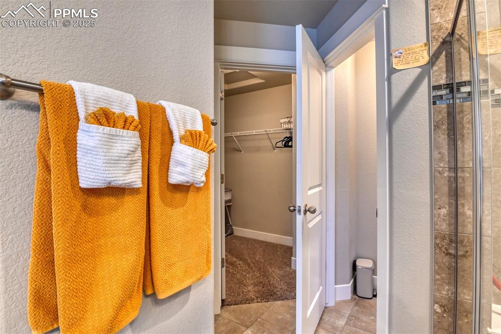 Image 23 of 45: Bathroom featuring a shower stall, a walk in closet, light tile patterned f