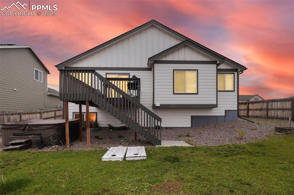 Image 4 of 45: Back of house with a hot tub, stairs, board and batten siding, and a wooden
