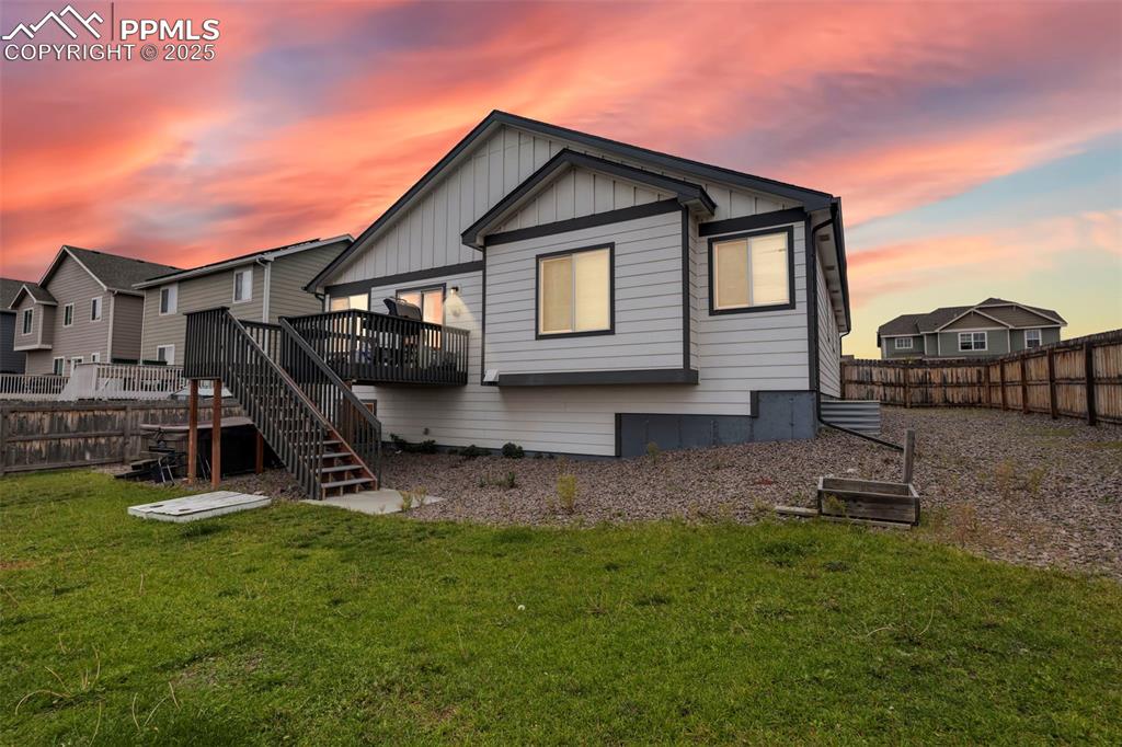 Image 5 of 45: Back of house at dusk featuring a fenced backyard, stairway, a deck, and bo