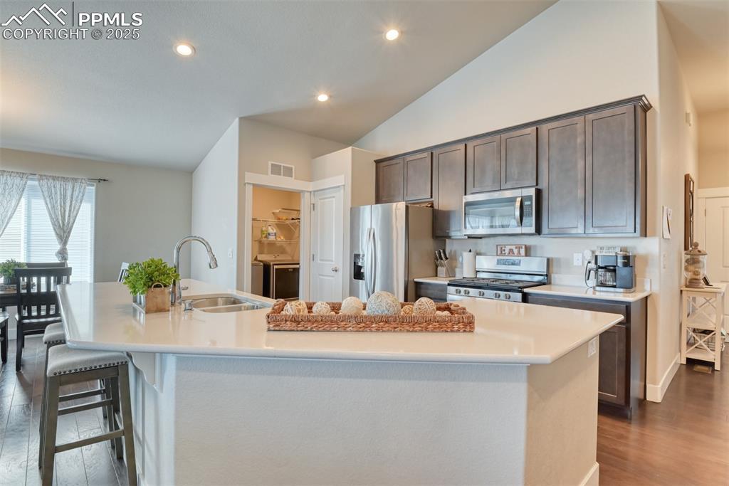 Image 9 of 45: Kitchen featuring dark wood finished floors, dark brown cabinetry, recessed
