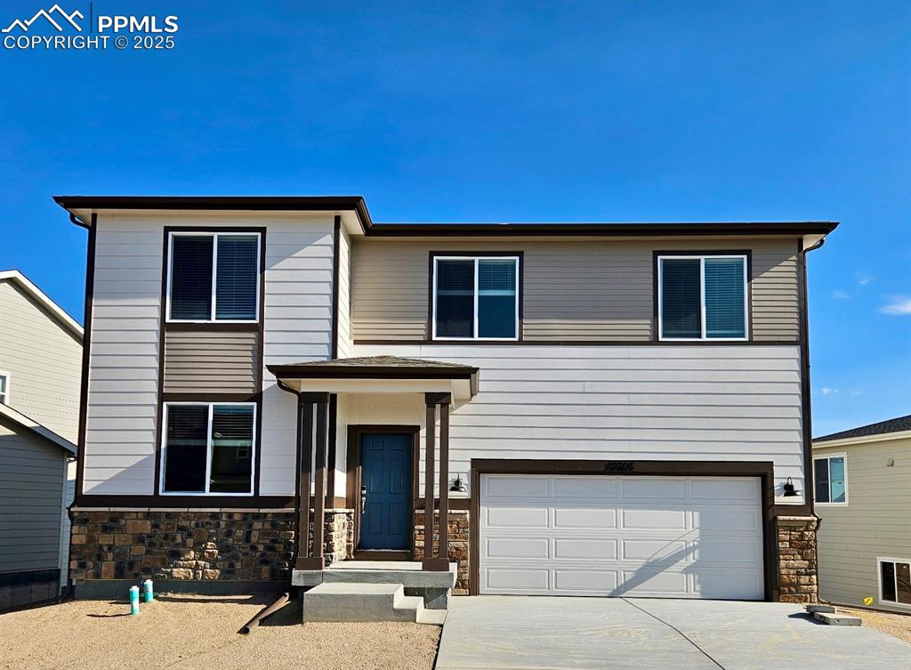 Caption: View of front of home with an attached garage, stone siding, and concrete driveway