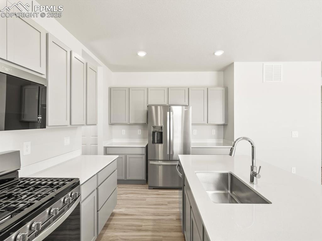 Image 12 of 44: Kitchen featuring appliances with stainless steel finishes, gray cabinetry,