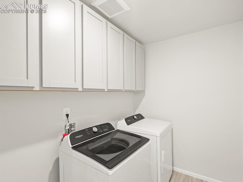 Image 40 of 44: Laundry area featuring separate washer and dryer, cabinet space, and light 