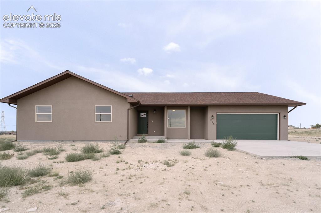 Caption: Stucco exterior with a peaked roofline, attached garage, and concrete driveway