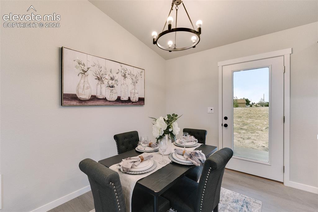 Image 12 of 28: Vaulted ceiling with a contemporary chandelier, wood-finish flooring, and a
