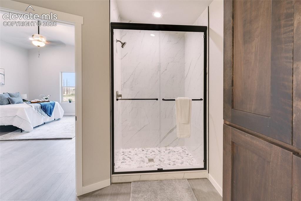Image 18 of 28: Walk-in shower with black-framed glass enclosure, stone pebble floor, and l