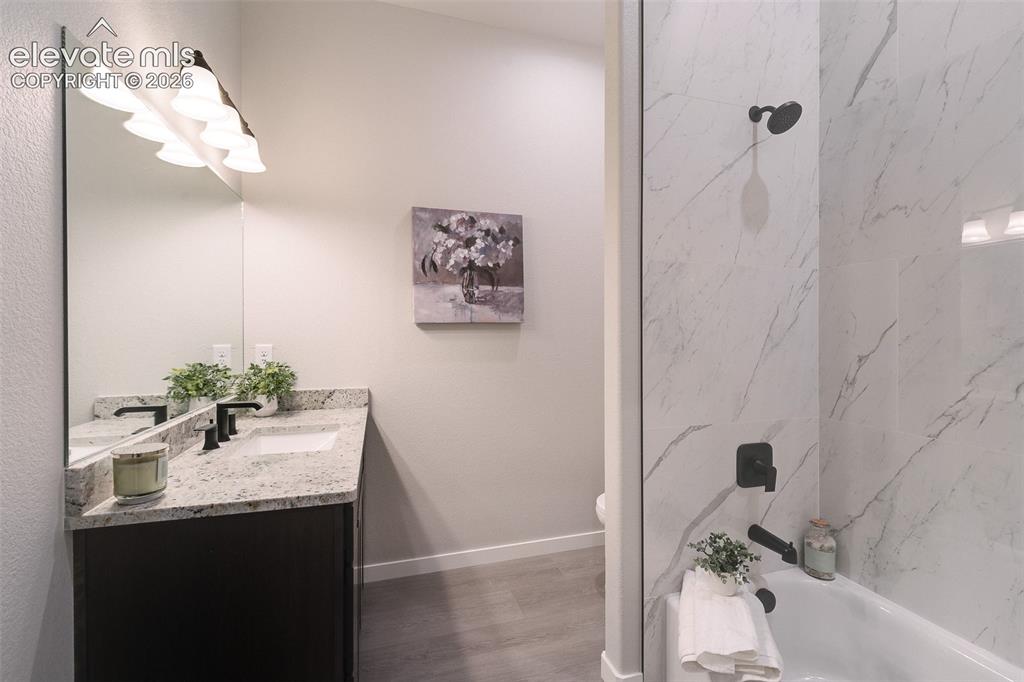 Image 22 of 28: Vanity with granite countertop and undermount sink, matte black faucet, and
