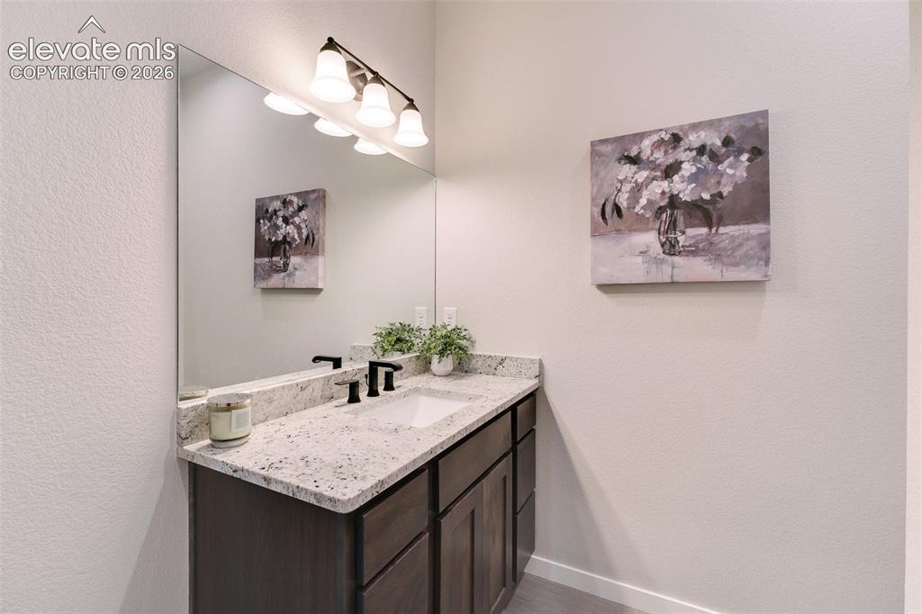 Image 23 of 28: Vanity with a speckled countertop, integrated sink, and dark wood-finish ca