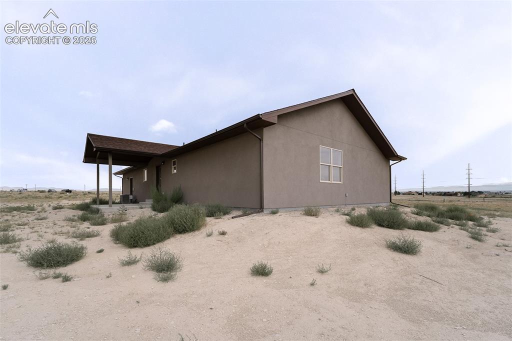 Image 27 of 28: Stucco exterior with a covered porch, pitched roof, and visible foundation