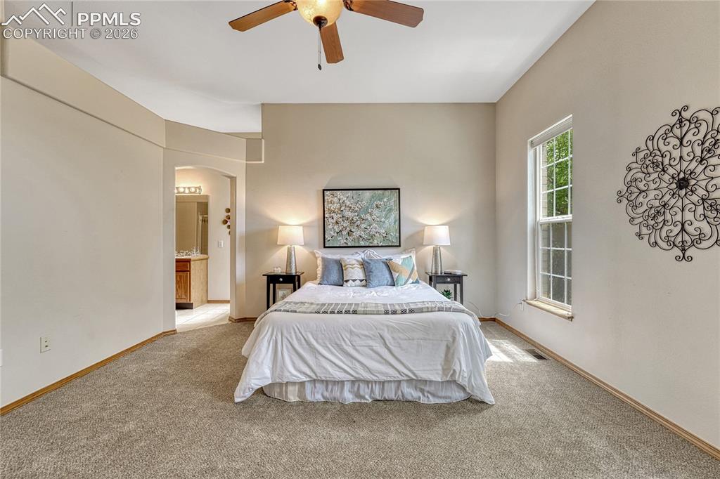 Image 19 of 48: Retreat to the luxurious main-level primary bedroom, which dazzles with bra