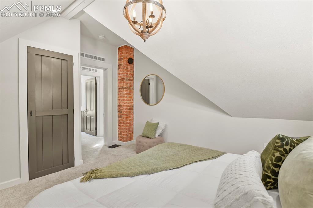 Image 27 of 40: Primary bedroom with exposed brick chimney 