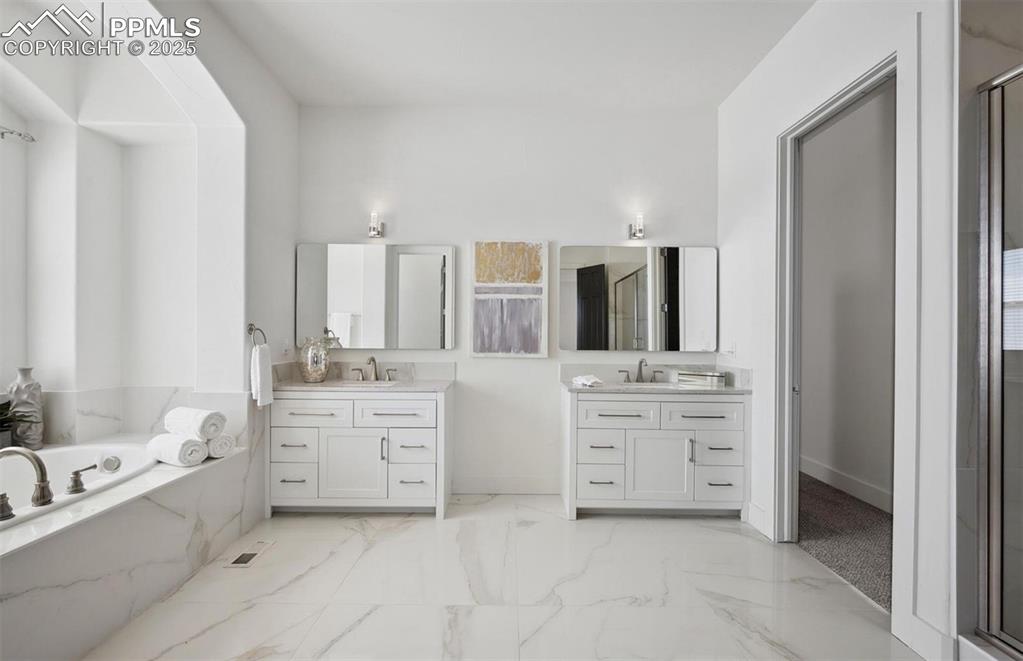 Image 10 of 31: Full bathroom with a bath, two vanities, and a marble finish shower