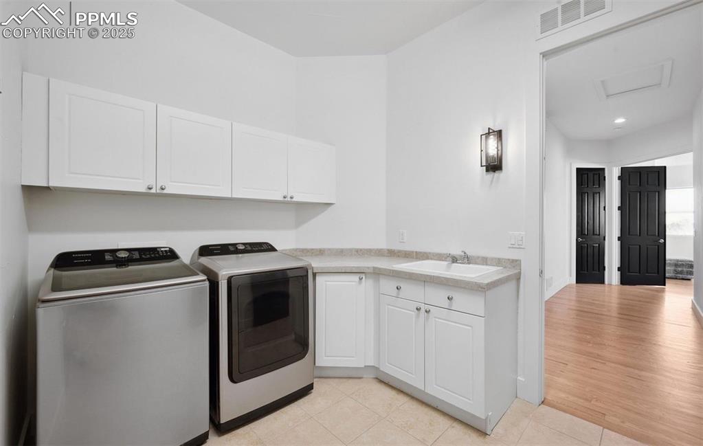 Image 16 of 31: Laundry room with light tile patterned floors, washing machine and clothes 