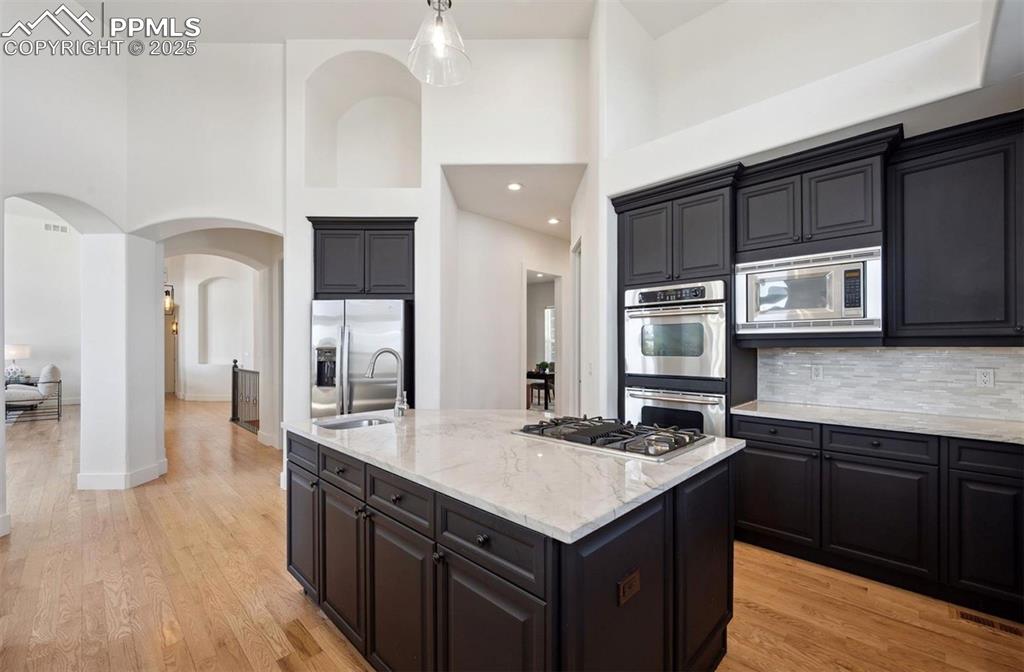 Image 4 of 31: Kitchen with a high ceiling, arched walkways, light stone counters, tastefu