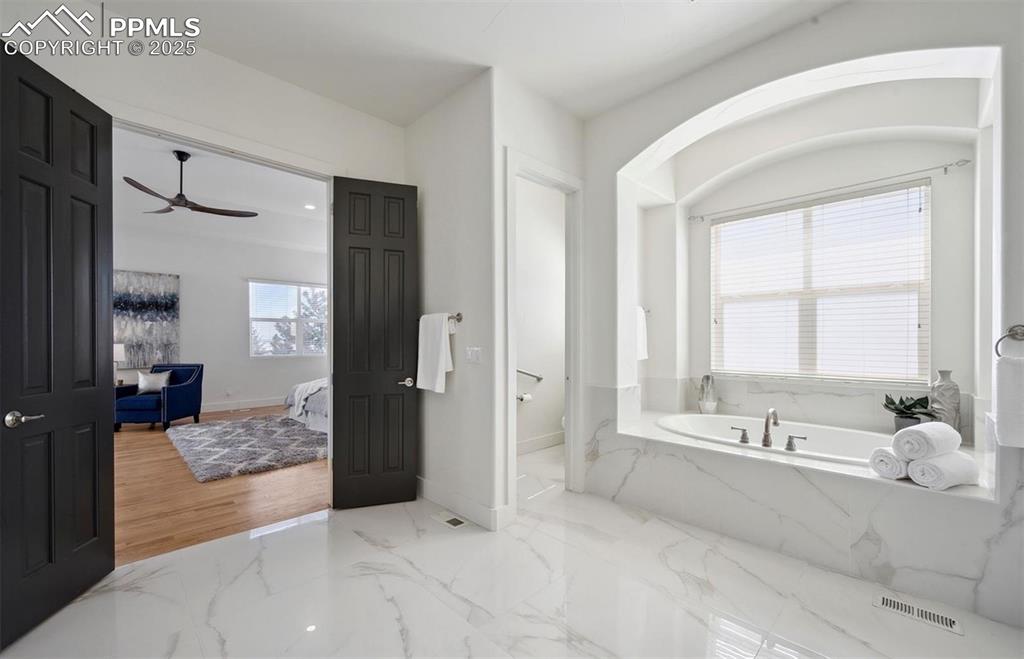 Image 9 of 31: Ensuite bathroom with light marble finish floors, a garden tub, and ceiling