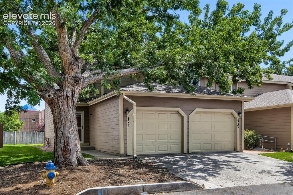 Image 1 of 35: Two-story residence featuring a two-car garage with panel doors and a paved
