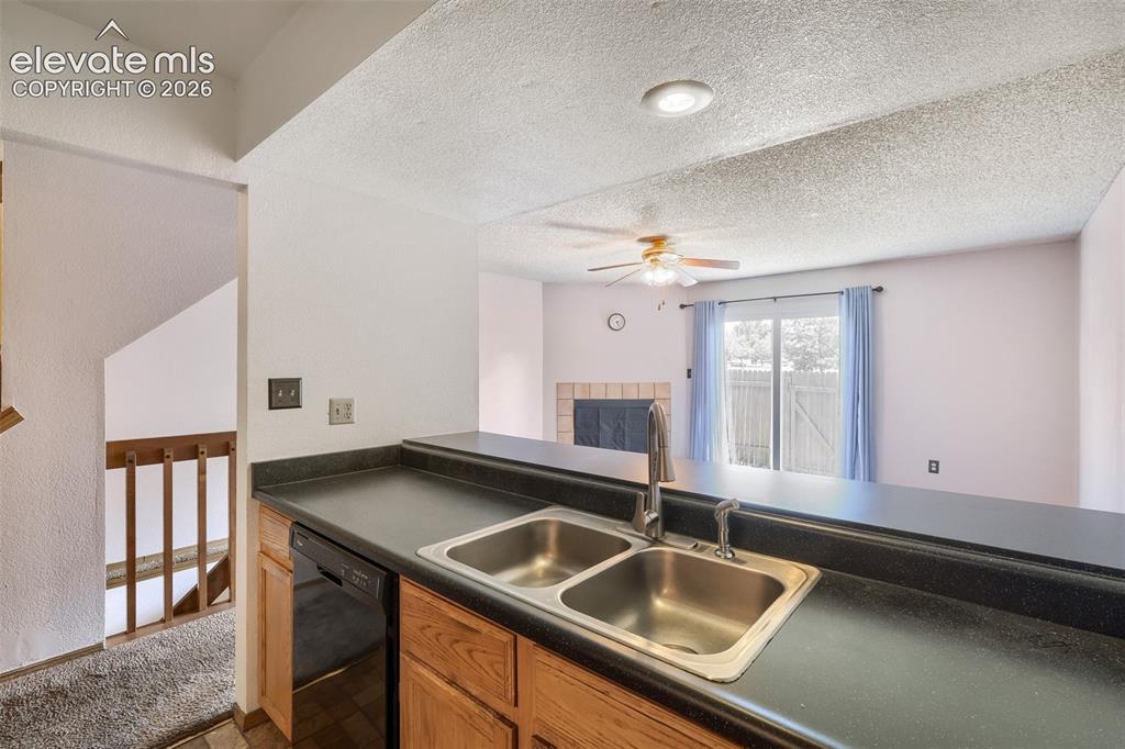 Image 12 of 35: Kitchen area featuring a double basin stainless steel sink, black counterto